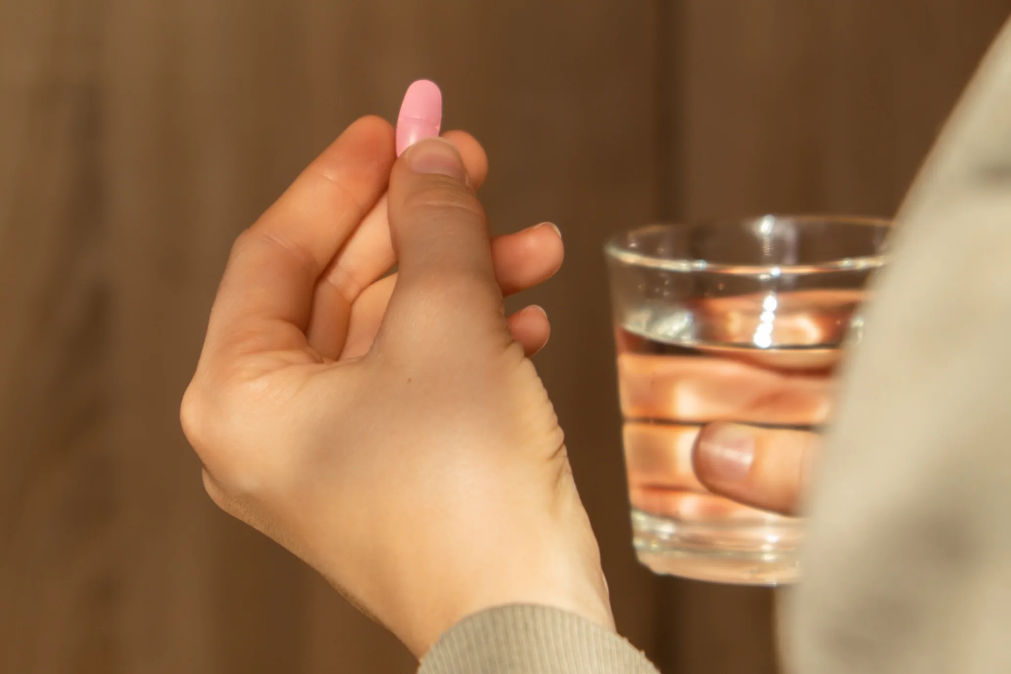 Patient holding a pill and a glass of water